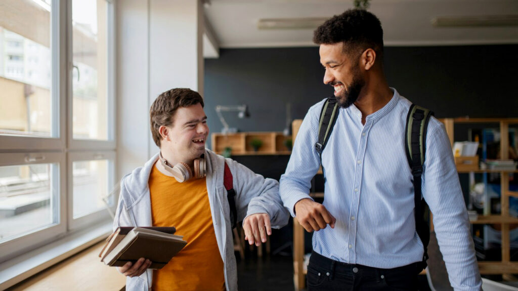 Support worker and client bumping elbows and smiling, sharing a moment of friendly connection and trust.